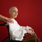 Crop assistant supporting smiling patient in wheelchair during rehabilitation process